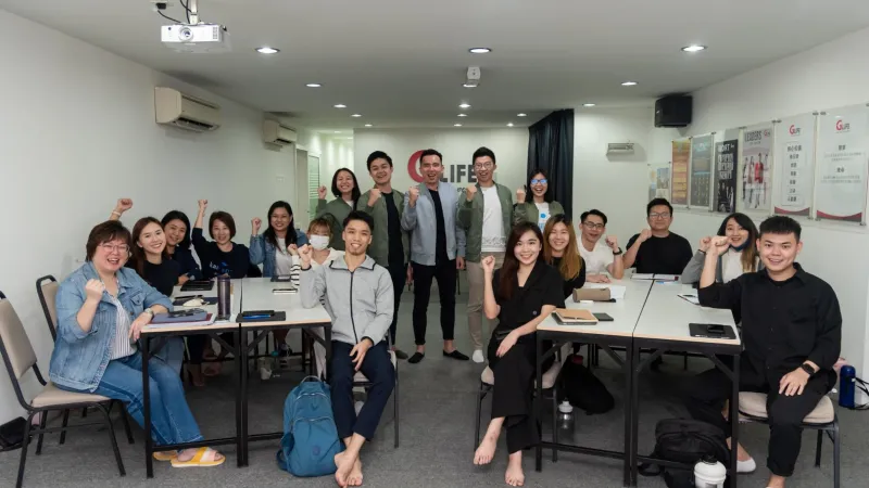 A training room of participants cheering together